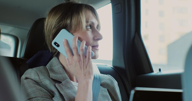 Beautiful businesswoman talking on the phone in car working on laptop Using technologies in the car concept