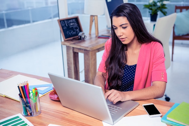 Beautiful businesswoman using laptop while working in creative office