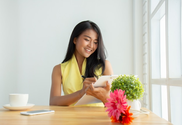 beautiful businesswoman wearing a yellow shirt is sitting in the office checking documents to check his business plans happily