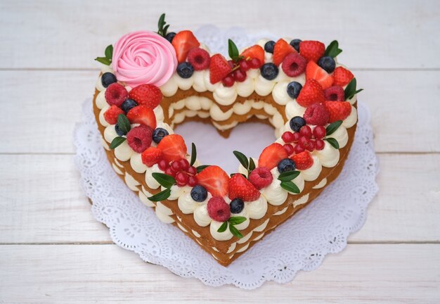 Beautiful cake in the form of a heart with cheese cream and berries