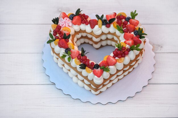 Beautiful cake in the form of a heart with cheese cream and berries