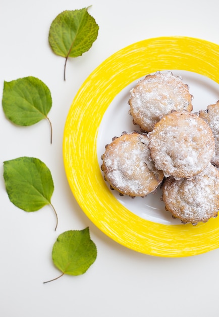 Beautiful cakes with powdered sugar on a yellow plate.