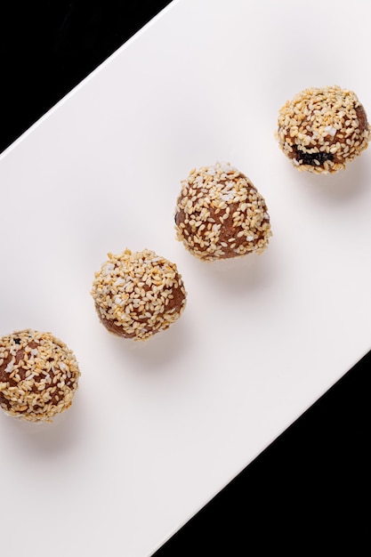 Beautiful candies with sesame seeds on a white plate on a black background