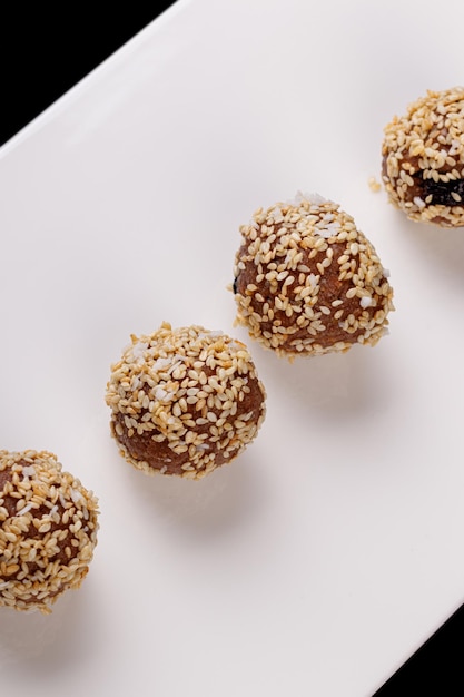 Beautiful candies with sesame seeds on a white plate on a black background