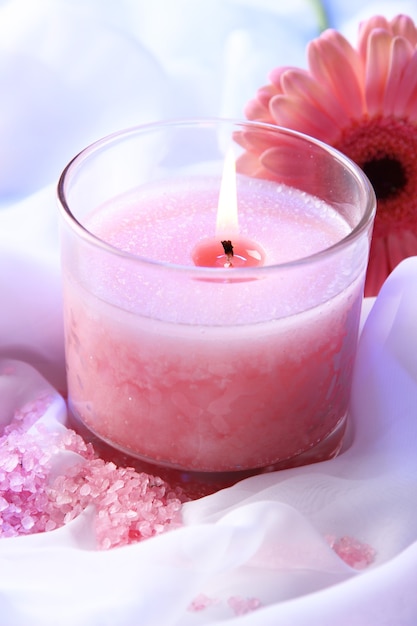 Beautiful candle with flower on white cloth, close up