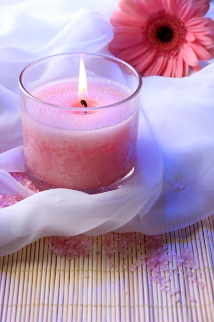 Beautiful candle with flower on white cloth, close up