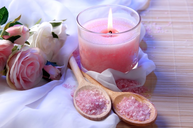 Beautiful candle with flowers on white cloth close up