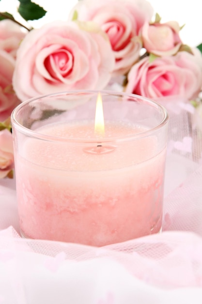 Beautiful candle with flowers on white cloth, close up