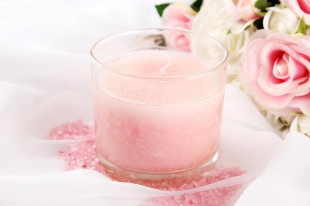 Beautiful candle with flowers on white cloth, close up