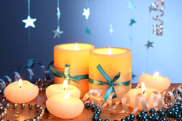 Beautiful candles, gifts and decor on wooden table on blue background