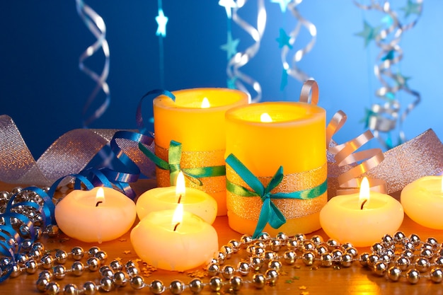 Beautiful candles, gifts and decor on wooden table on blue background