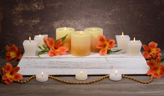 Beautiful candles with flowers on table on brown background