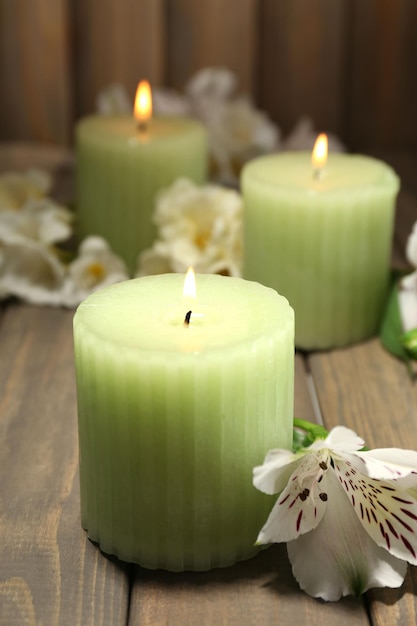 Beautiful candles with flowers on wooden background