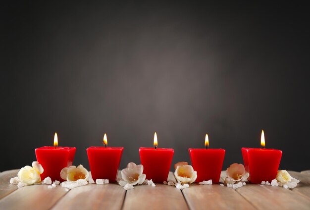 Beautiful candles with flowers on wooden background