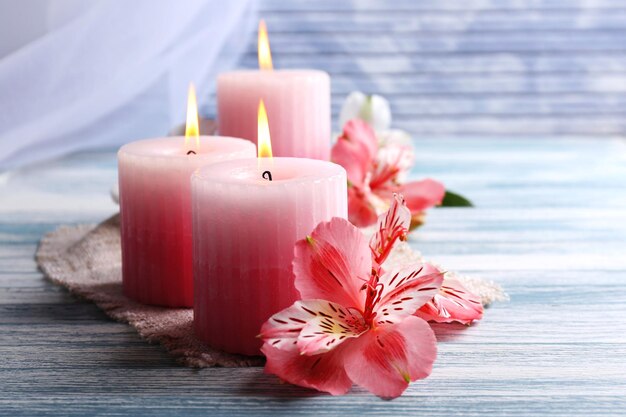 beautiful candles with flowers on wooden background