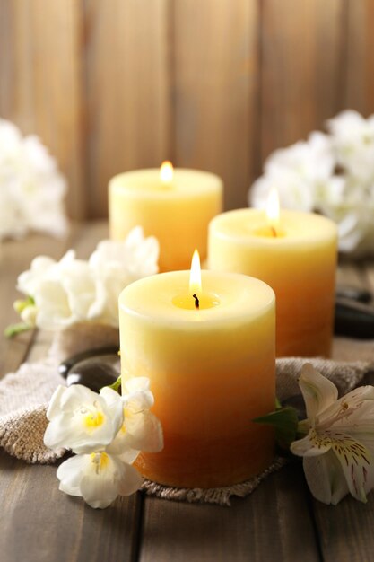 Beautiful candles with flowers on wooden background