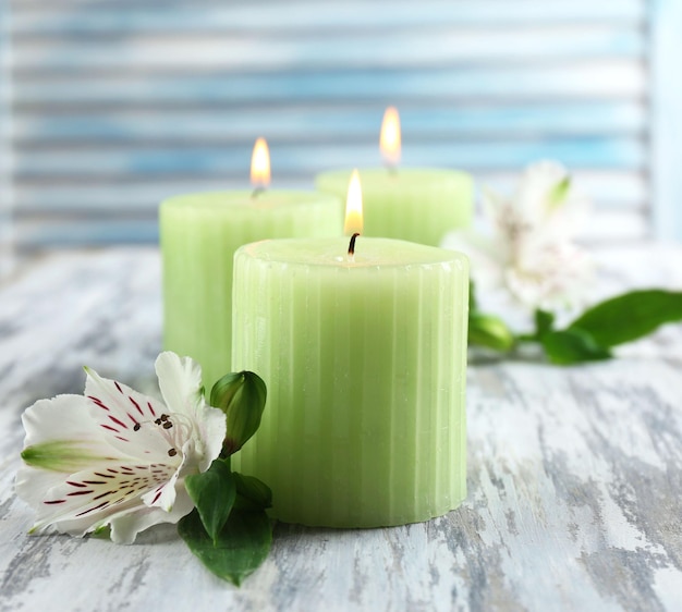 Beautiful candles with flowers on wooden background