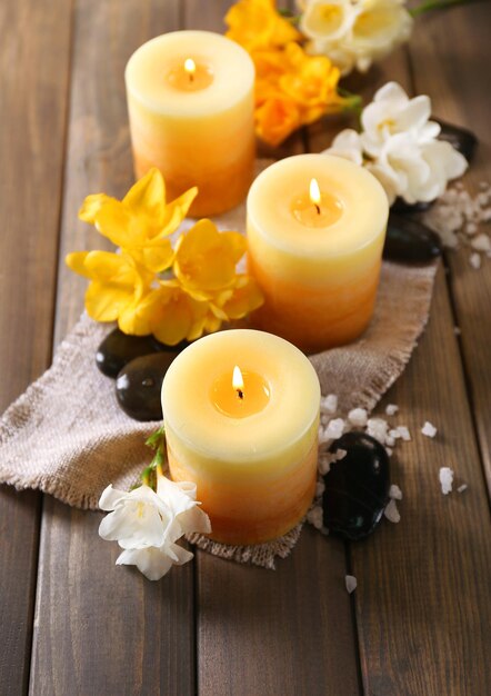 Beautiful candles with flowers on wooden background