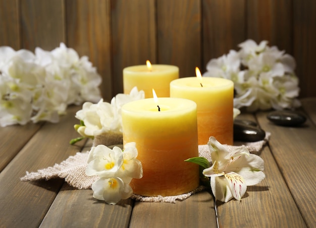 Beautiful candles with flowers on wooden background