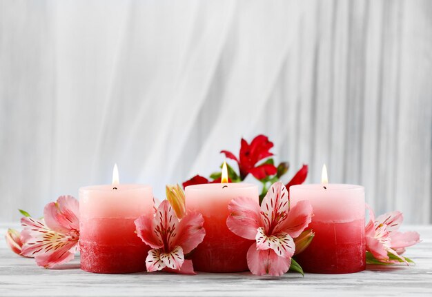 Beautiful candles with flowers on wooden table, on dark background