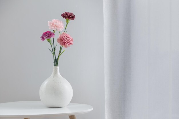 beautiful carnation flowers in ceramic vase on white table