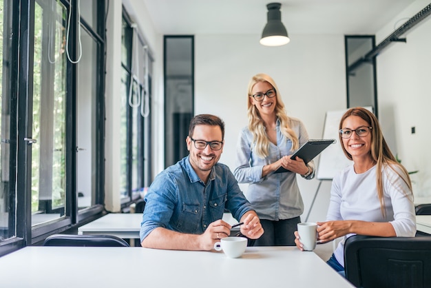 Beautiful casual business people in modern bright office. Looking at camera. Teamwork concept.