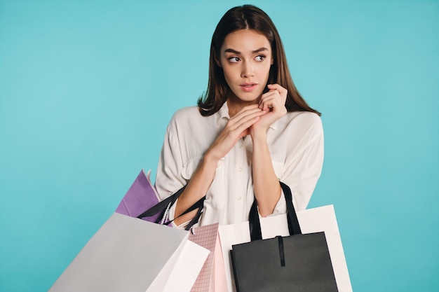 Beautiful casual girl with shopping bags thoughtfully looking away over colorful background