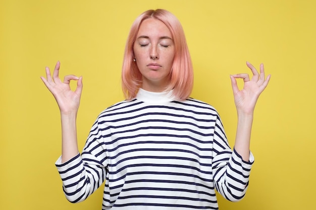 Foto bella giovane donna vestita in modo casual che tiene gli occhi chiusi mentre medita sentendosi rilassata