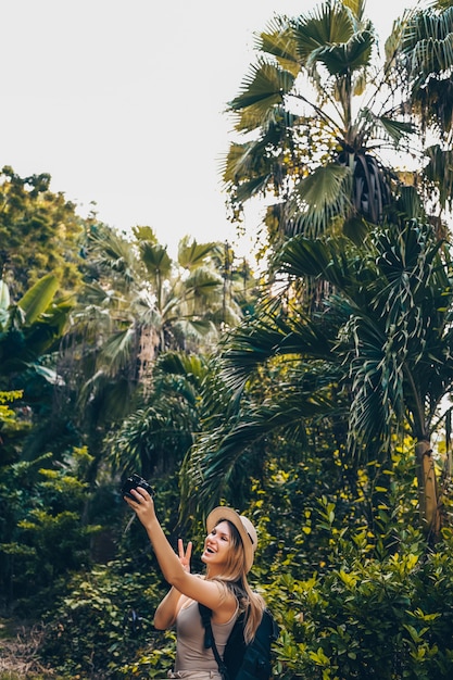 아름 다운 백인 금발 여자 아시아 여행 배낭 여행자 여자 삼아 정글에서 사진을 찍고 즐기는 산책. 아시아를 따라 여행, 활동적인 라이프 스타일 개념. 중국 하이난 발견