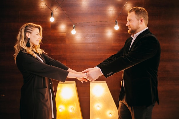 beautiful caucasian couple in love in white shirts and black jackets on a wooden background