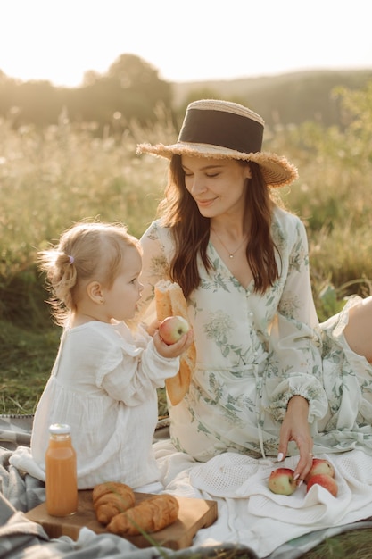 Beautiful caucasian family of father mother and little daughter posing on camera on background of green field