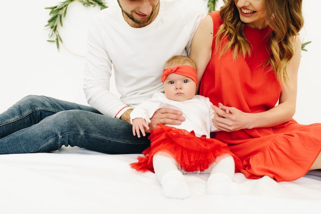 Beautiful caucasian family of mother, father and daughter sitting in matching outfits