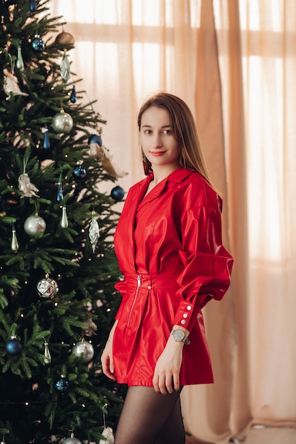 Beautiful caucasian female poses near the christmas tree at home