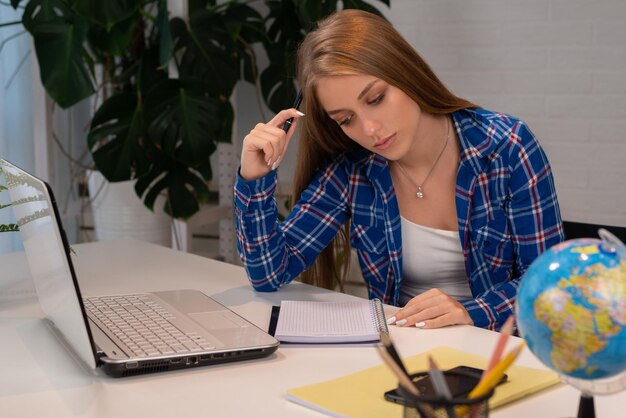 A beautiful caucasian female student is studying in college remotely