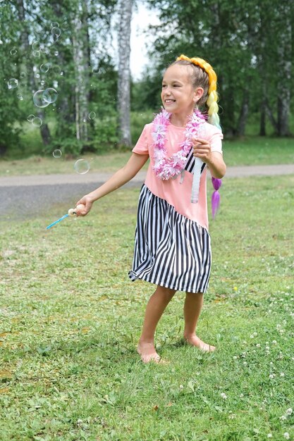 写真 美しい白人の女の子がソープの泡を吹き飛ばしている ハワイのレイ花の花束を着た茶色の女の子