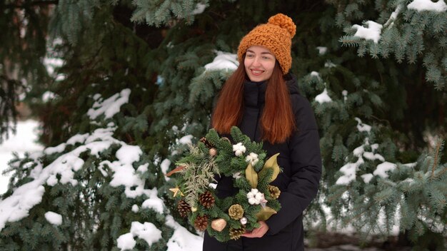 Beautiful caucasian girl and christmas wreath outdoors o na snowy day