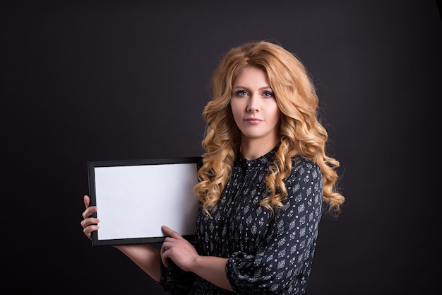 Beautiful caucasian girl holding an empty white blank, a place for advertising