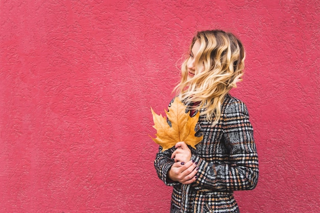 Photo beautiful caucasian girl holding a yellow autumn leaf in her hands