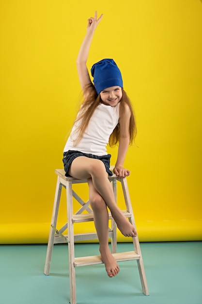 Beautiful caucasian girl posing in studio on a yellow isolated background