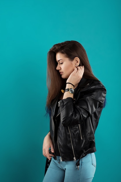 Beautiful caucasian girl with long dark hair and in black leather jacket posing