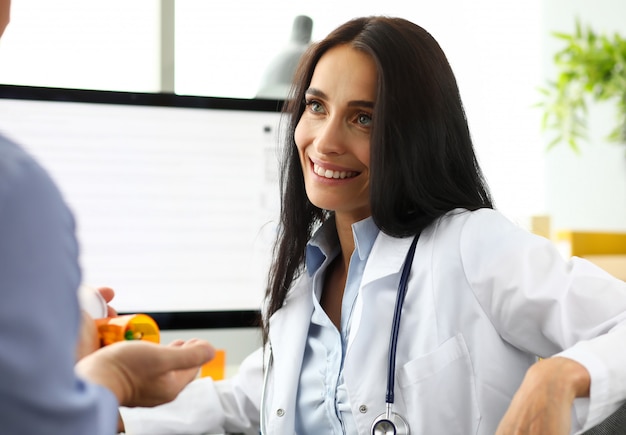 Beautiful caucasian GP talking with male visitor giving him prescription portrait