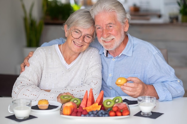 Bella coppia senior in pensione caucasica che fa colazione a casa con latte di frutta fresca di stagione e concetto di alimentazione sana cupcake