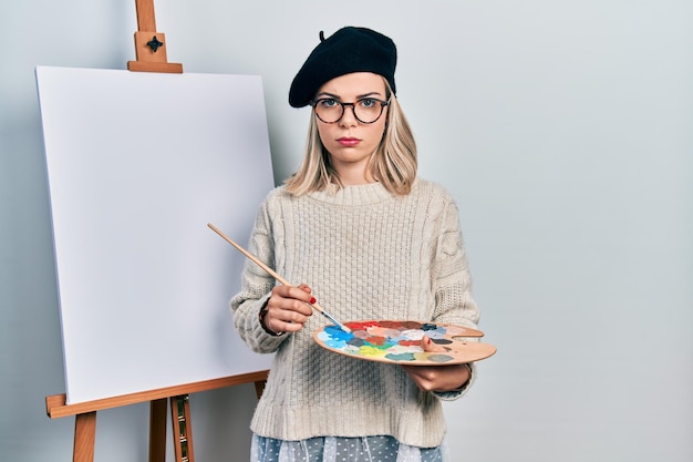 beautiful caucasian woman drawing with palette on easel stand depressed and worry for distress crying angry and afraid sad expression