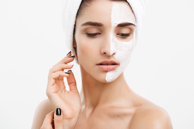 Beautiful Caucasian Woman Face Portrait applying cream mask on her facial skin white background.