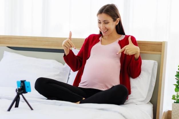 Bella donna caucasica felicemente incinta durante una videochiamata sul suo smartphone le nuove mamme comunicano in modalità wireless con i moderni dispositivi di comunicazione