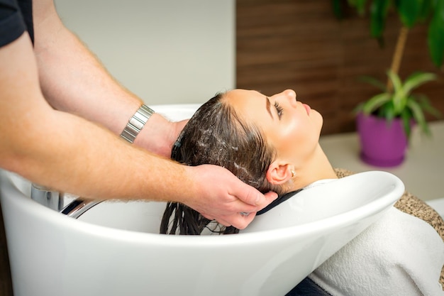 Beautiful caucasian woman washing hair in a beauty salon.