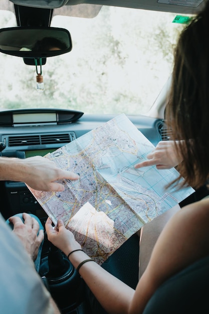 Beautiful caucasian young hipster female posing during a car\
trip checking the map to see their next location . van life\
lifestyle. travel and happiness concept. glasses during a sunset\
day