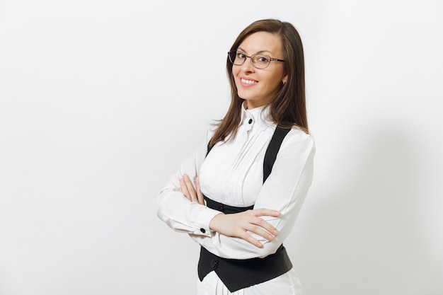 Bella giovane caucasica sorridente donna d'affari dai capelli castani in abito nero, camicia bianca e occhiali che si tengono per mano incrociati isolati su sfondo bianco. dirigente o lavoratore. copia spazio per la pubblicità.