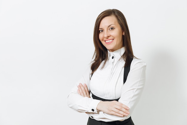 Beautiful caucasian young smiling brown-hair business woman in black suit, white shirt with crossed hands looking camera isolated on white wall