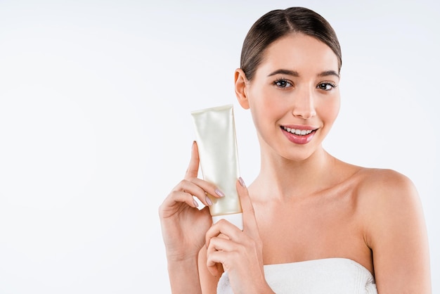 Beautiful caucasian young woman face portrait holding and presenting cream tube product